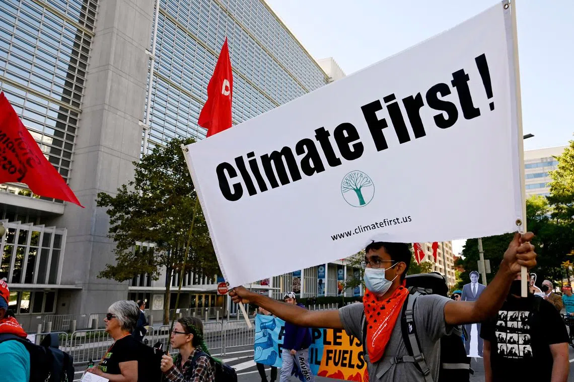 Climate activists protest outside the World Bank headquarters against fossil fuel projects during the IMF and World Bank annual meetings in Washington, DC on October 14, 2022. (Photo by OLIVIER DOULIERY / AFP)