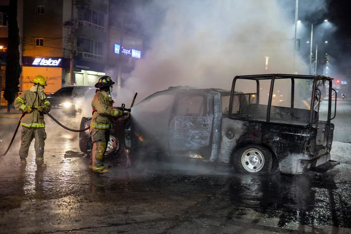 Firefigthes put out a van stolen and set on fire by alleged students of the "Isidro Burgos" Normal Rural School of Ayotzinapa in Chilpancingo, State of Guerrero, Mexico on March 7, 2024. The Secretary of State Public Security, Rolando Solano, confirmed that the unit where the people were transported has a report of theft. In addition, a firearm and some bags containing a granulated substance were located, which will be analyzed by the State Attorney General's Office, who will carry out the investigations. (Photo by EDUARDO GUERRERO / AFP)