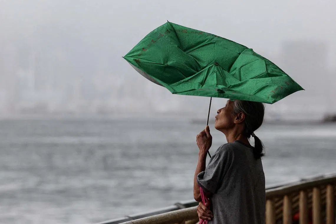 A woman holds an umbrella inverted by winds as Tropical Storm Tapah approaches in Hong Kong, China, September 8, 2025. REUTERS/Tyrone Siu TPX IMAGES OF THE DAY