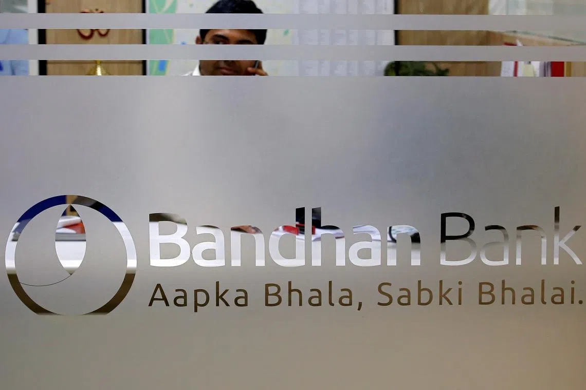 An employee of Bandhan Bank is seen behind a glass bearing the bank's logo inside a branch office in Kolkata, India, March 8, 2018. REUTERS/Rupak De Chowdhuri/File Photo