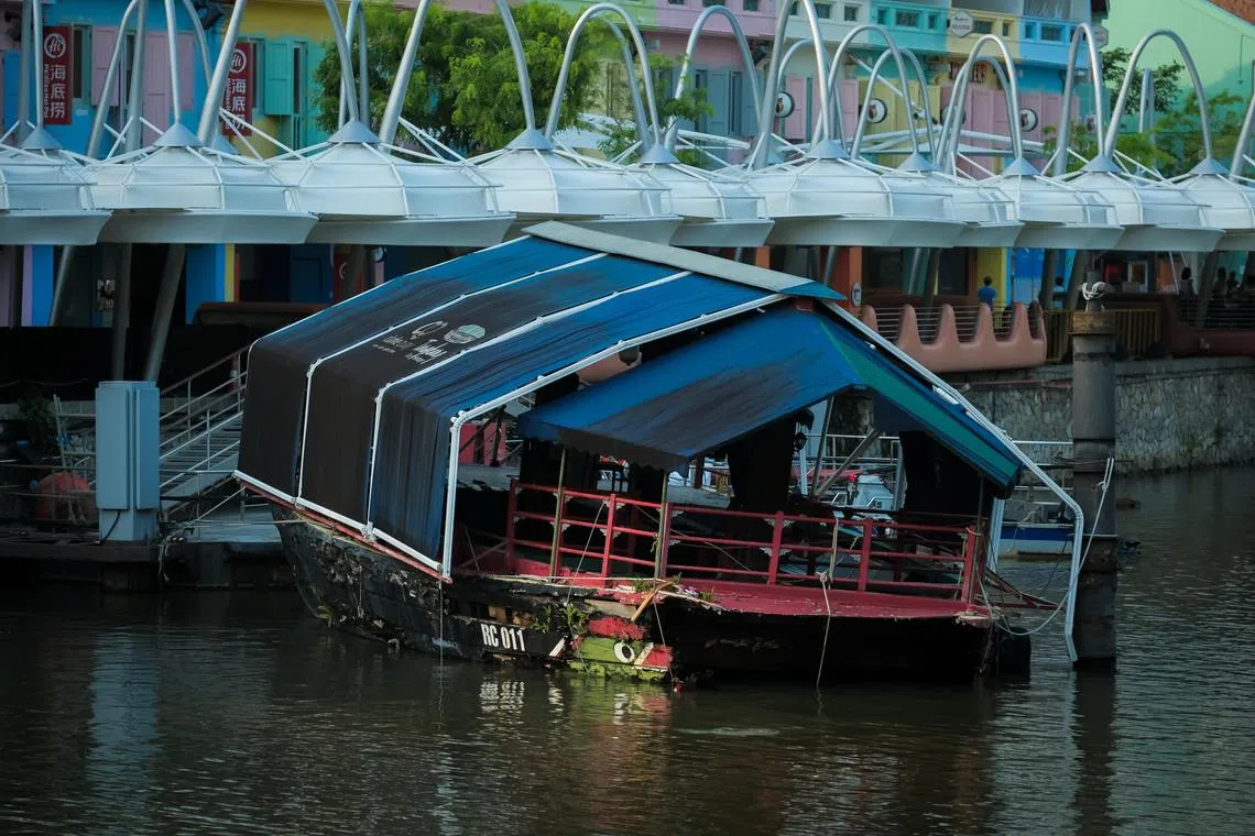 One of the two boats berthed at Clarke Quay which were being used as eateries, June 19, 2023. The boat is seen tilted and partially sunken.  Capitaland who owns them, says they are beyond repair and will be getting rid of them.