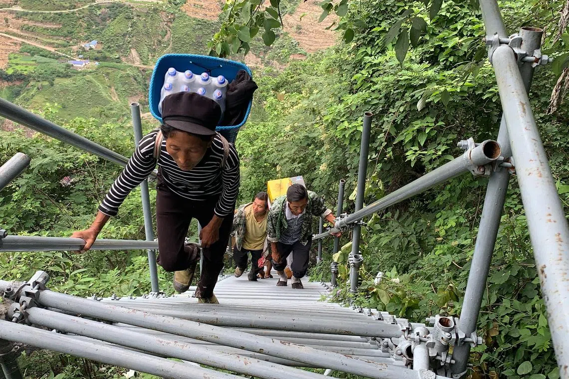 Villagers climbing a series of steel stairs and ladders to reach their homes in the village of Atulie’er in the Liangshan Yi Autonomous Prefecture in Sichuan province, China.