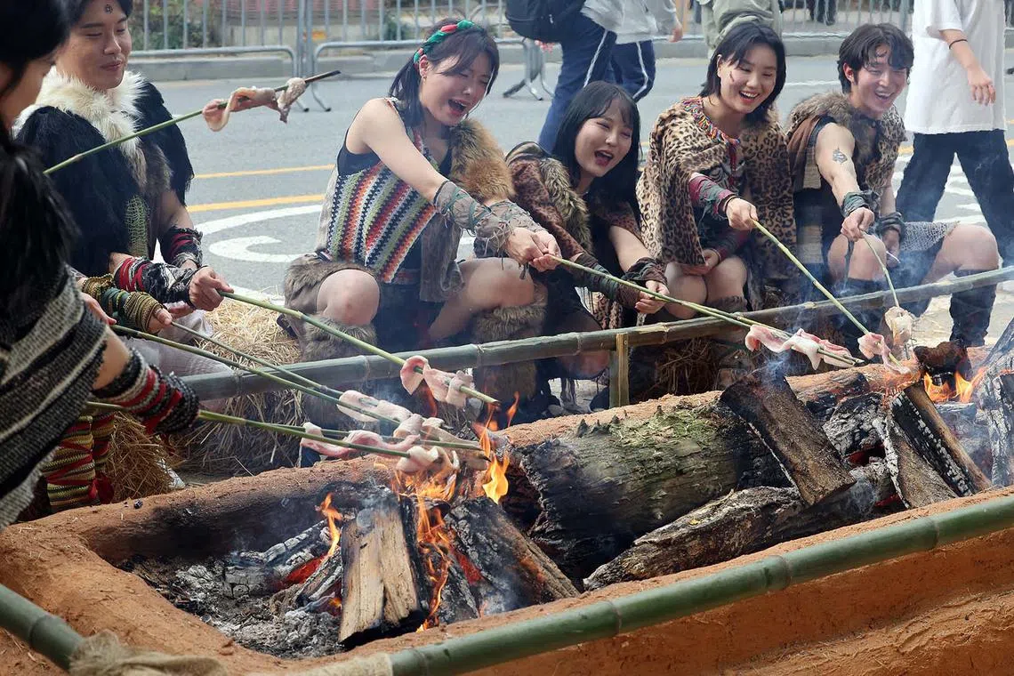 People having a barbecue as they experience what life was like in ancient times during a prehistoric culture festival at the remains of the Prehistoric Settlement Site, where visitors can learn about life in the Neolithic era, in the Gangdong Ward in Seoul, South Korea, Oct 13.