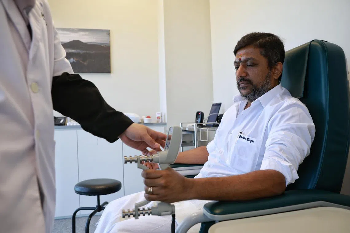 Mr JK Saravana (right), 41-year-old businessman, having his hand grip strength recorded by research assistant Halimah Ibrahim at the launch of SG100K study by Nanyang Technological University’s Lee Kong Chian School of Medicine (LKCMedicine) in collaboration with other healthcare institutions on Dec 16, 2022.