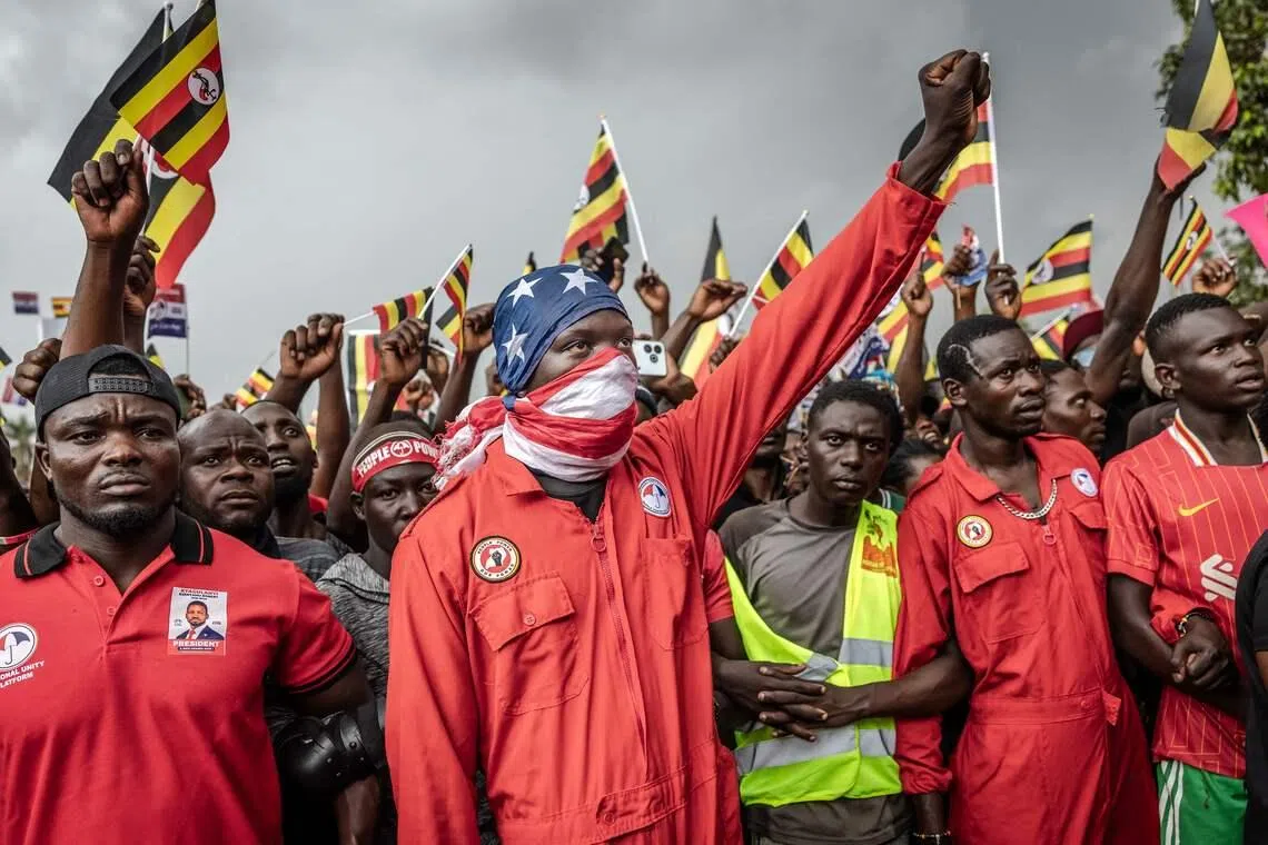 A supporter of Uganda opposition leader and National Unity Platform (NUP) presidential candidate Robert Kyagulanyi Ssentamu, raising a clenched fist while covering his face with a US flag during the party’s final campaign rally, ahead of the 2026 general elections, in Kampala, on Jan 12, 2026. 