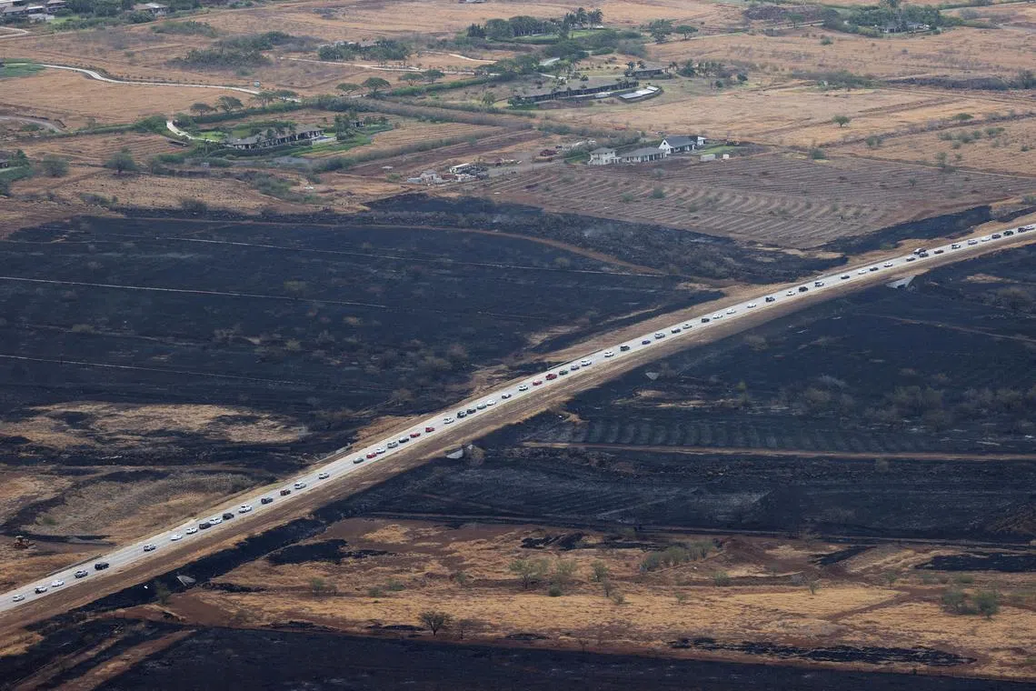 Cars driving away from Lahaina after wildfires driven by high winds burned across most of the town, Aug 10.