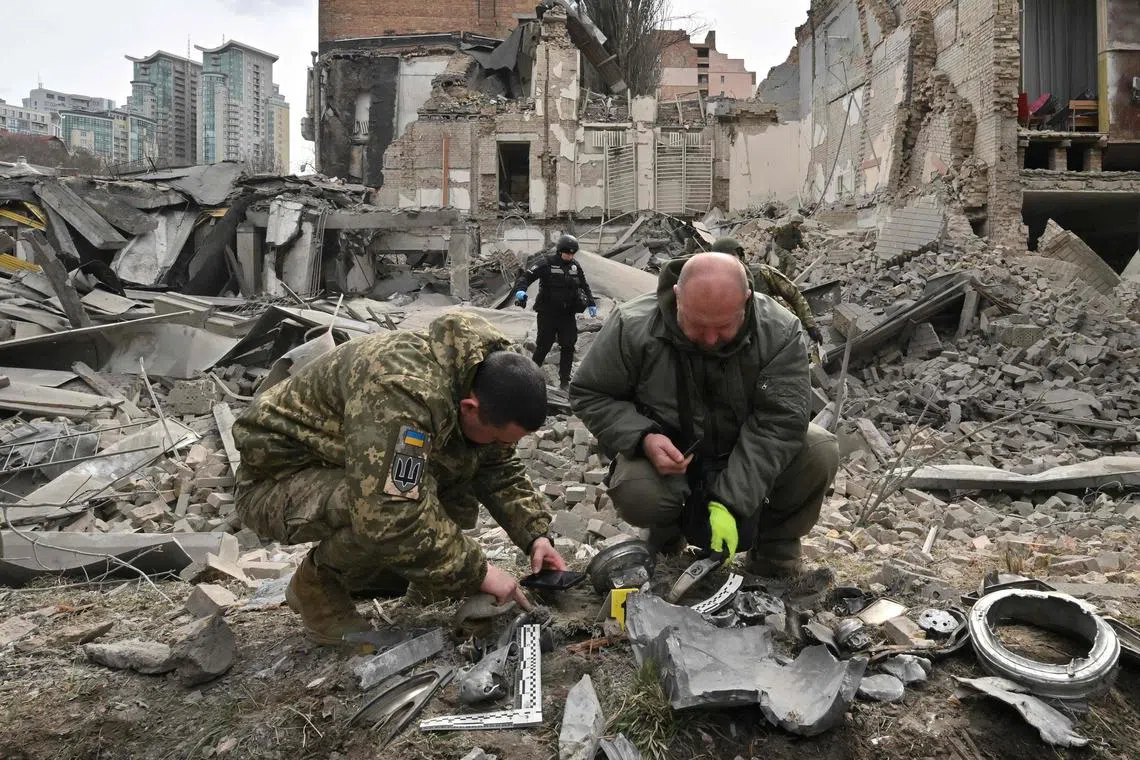 Ukrainian law enforcement officers examine fragments of a rocket at the site of a missile attack in Kyiv on March 25, 2024, amid the Russian invasion of Ukraine. Five people including a teenage girl were injured on March 25, 2024 during a Russian missile attack on Kyiv, where falling debris also damaged at least two buildings in central districts. Russia has escalated aerial attacks on Kyiv in recent days, targeting key infrastructure in the wake of fatal Ukrainian bombardments on Russian border regions. (Photo by Sergei SUPINSKY / AFP)