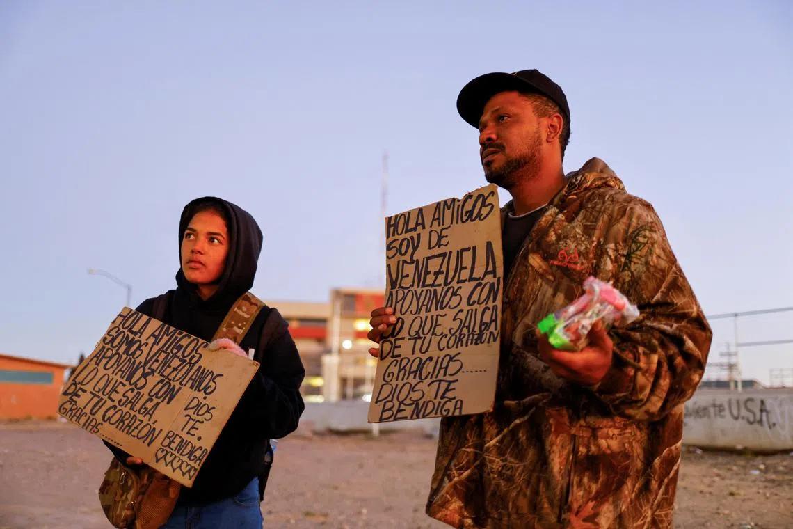 Julio Marquez and Yalimar Chirinos, migrants from Venezuela, display signs near the border between the United States and Mexico, in Ciudad Juarez, Mexico, January 7, 2023. The sign reads "Hello friends, we are from Venezuela, support us with what comes out from your heart". REUTERS/Jose Luis Gonzalez