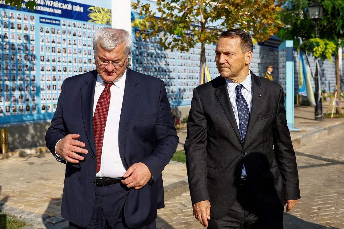 Ukrainian Foreign Minister Andrii Sybiha (left) and Polish Foreign Minister Radoslaw Sikorski visiting the Memory Wall of Fallen Defenders of Ukraine, in Kyiv, on Sept 13.