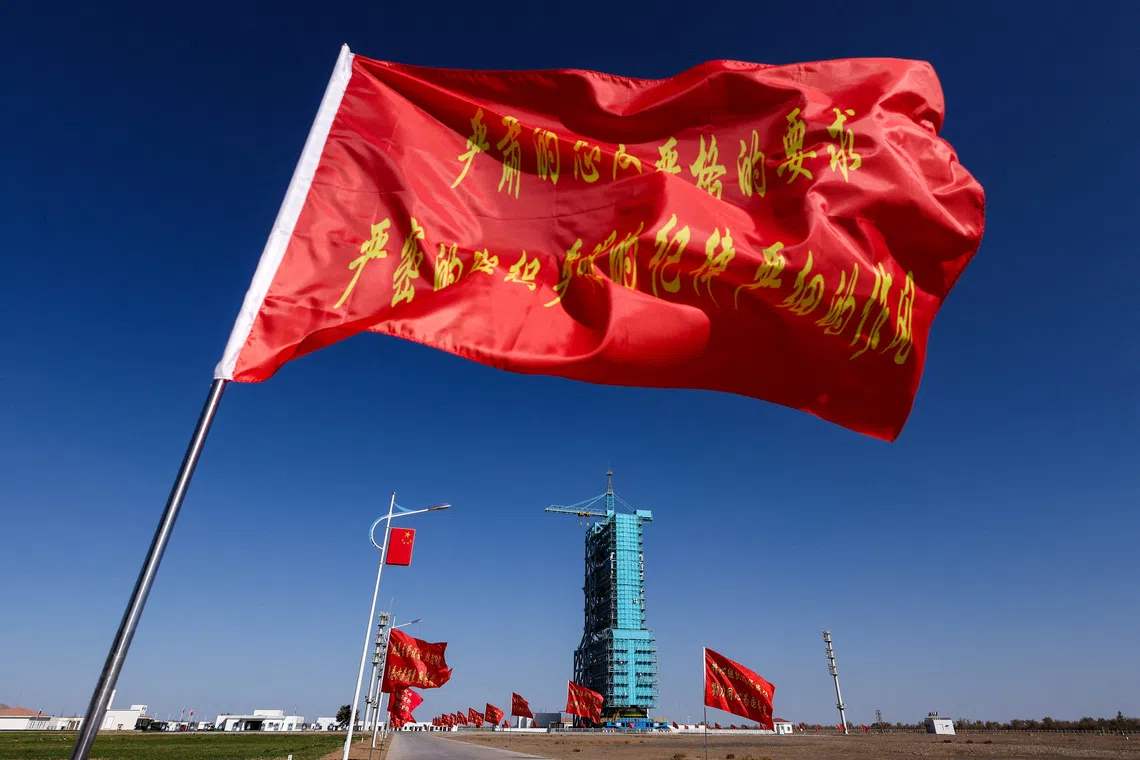 FILE PHOTO: Flags fly along the road near the launch pad for the Long March-2F rocket, ahead of the Shenzhou-21 spaceflight mission to China's Tiangong space station, at the Jiuquan Satellite Launch Center, near Jiuquan, Gansu province, China, October 30, 2025. REUTERS/Maxim Shemetov/File Photo