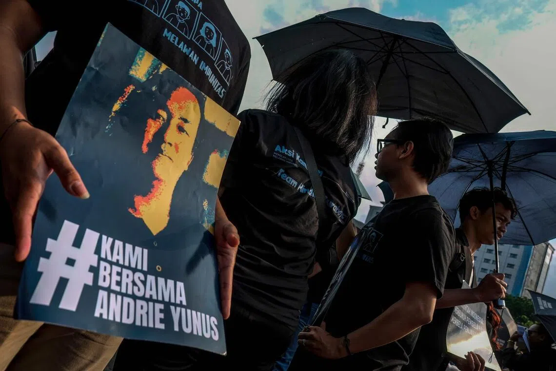 Activists hold black umbrellas and posters during a protest in front of the Presidential Palace in Jakarta on April 30.