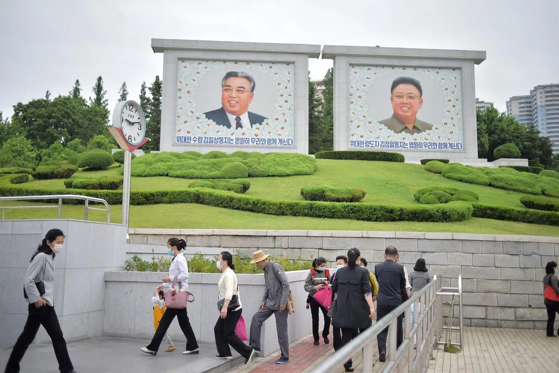 Pedestrians walk past the portraits of late North Korean leaders Kim Il Sung and Kim Jong Il in Pyongyang.