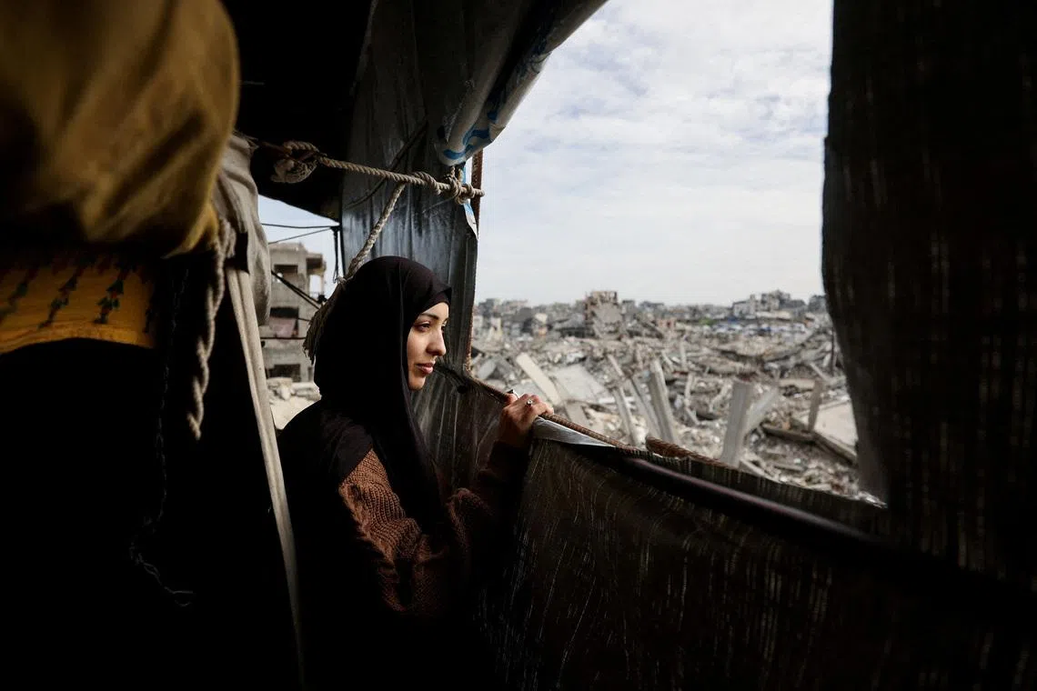 Palestinian mother of three, Eatedal Rayyan, 29, sits and looks out from a window of a tent set up inside her war-damaged home, following her return from medical treatment in Egypt, after nearly two years away, in northern Gaza Strip, February 6, 2026. REUTERS/Dawoud Abu Alkas