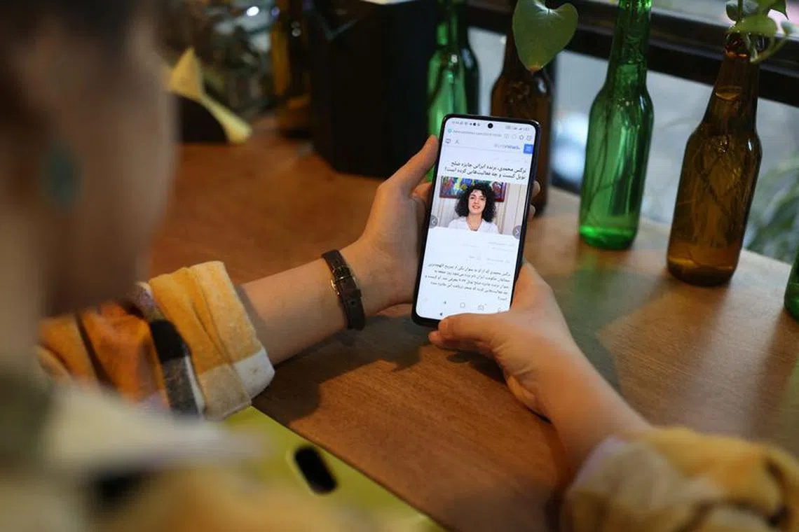 An Iranian woman sees the news of Iranian activist Narges Mohammadi winning the Nobel Peace Prize on her mobile phone, in a cafe in Tehran, Iran, October 6, 2023. Majid Asgaripour/WANA (West Asia News Agency) via REUTERS.