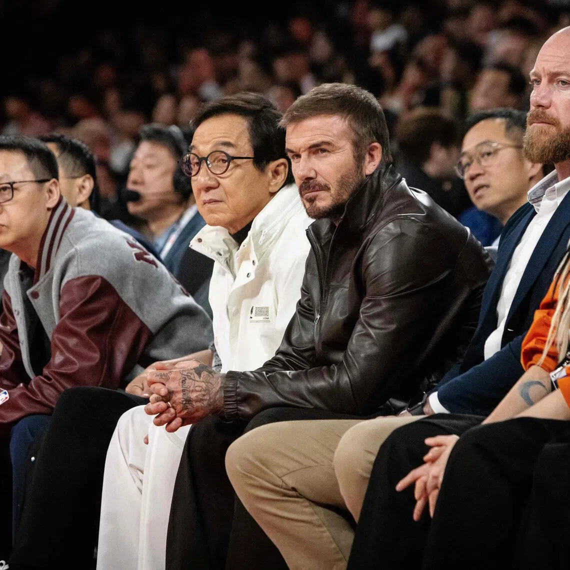 Jackie Chan and David Beckham watch from the front row the game between the Phoenix Suns and the Brooklyn Nets, at the Venetian Arena in Macau.