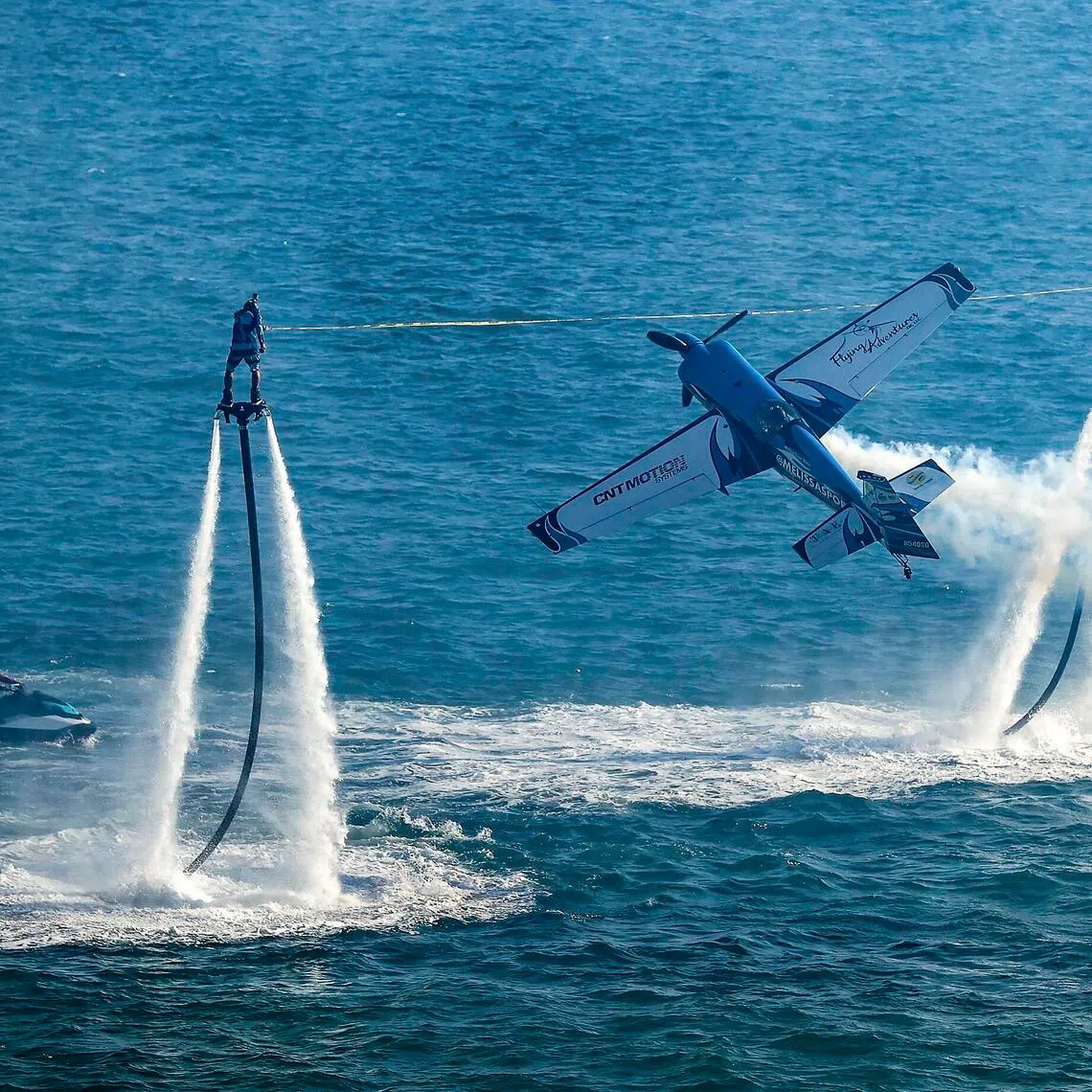 epa12545047 An aerobatic plane performs as two people fly using waterjets in the Acapulco AirShow 2025 in Santa Lucia Bay in Acapulco, Mexico, 23 November 2025. The show had not been held since 2018; the 2023 edition was suspended after Hurricane Otis struck the region. The event features aerobatic planes, fighter jets and skydiving.  EPA/DAVID GUZMAN