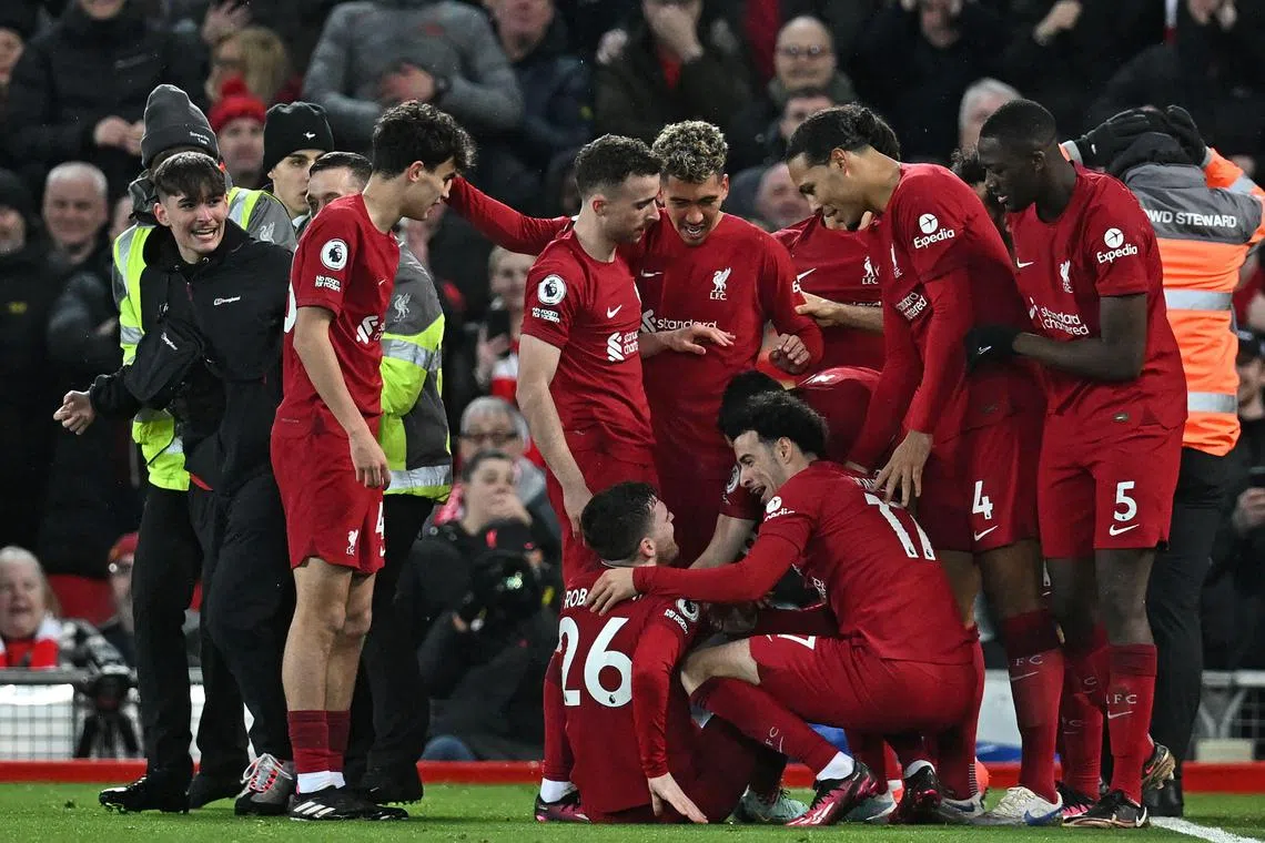 A pitch invader being taken away by stewards after colliding with Liverpool players celebrating their seventh goal during the English Premier League match between Liverpool and Manchester United at Anfield on Sunday. 