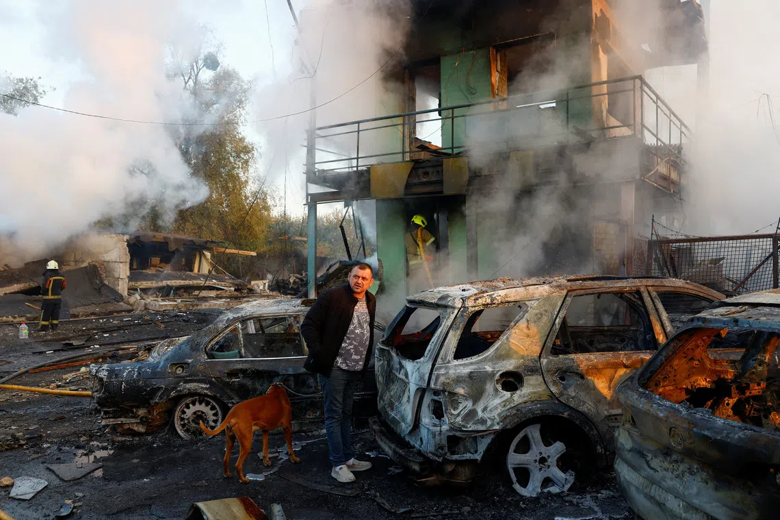 A resident with a dog looks on at the site of private car garages hit by a Russian missile strike, amid Russia's attack on Ukraine, in Kyiv, Ukraine October 7, 2026. REUTERS/Valentyn Ogirenko     TPX IMAGES OF THE DAY