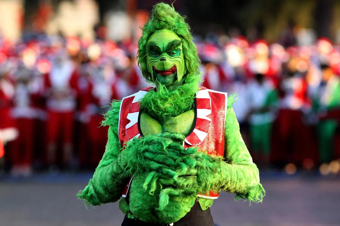 A runner dressed as The Grinch poses for a picture during the the annual "Run Santa Run" Christmas race in Zapopan, Mexico, on Dec 11, 2022. 