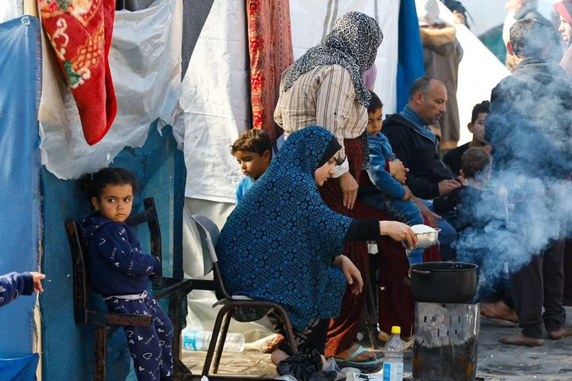 FILE PHOTO: A woman cooks as Palestinians, who fled their houses amid Israeli strikes, shelter at a United Nations-run school, amid the ongoing conflict between Israel and the Palestinian Islamist group Hamas, in Khan Younis, in the southern Gaza Strip, December 4, 2023. REUTERS/Ibraheem Abu Mustafa/File Photo
