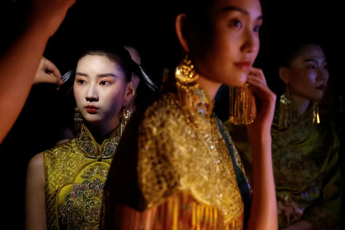 Models prepare as they put makeup backstage before the LOOLAYY Autumn/Winter 2023 collection show by Xiaoqi Zhang, during China Fashion Week in Beijing, China March 30.