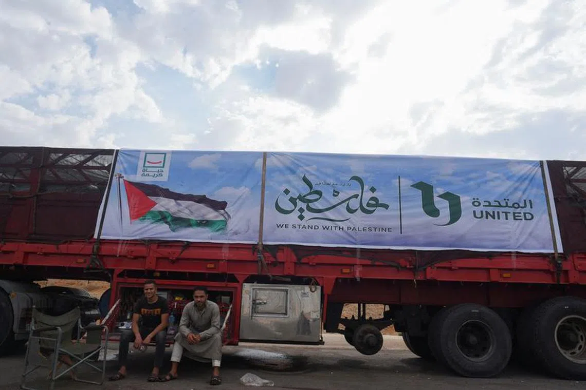 People rest near a truck carrying humanitarian aid to Palestinians, on a desert road (Cairo - Ismailia) on the way to the Rafah border crossing to enter Gaza, amid the ongoing conflict between Israel and the Palestinian Islamist group Hamas, in Cairo, Egypt, November 12, 2023. REUTERS/Hadeer Mahmoud/file photo