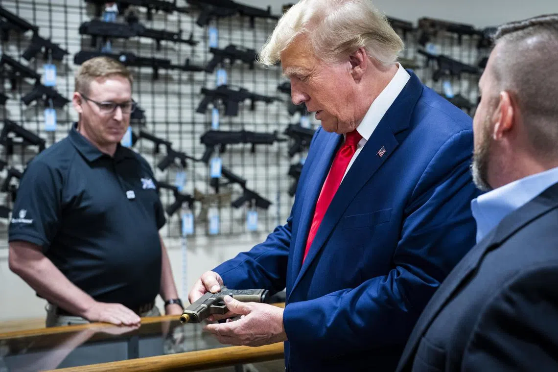 Former President Donald Trump, a Republican presidential candidate, examines a customized Glock pistol decorated with his name and likeness during a visit the Palmetto State Armory location in Summerville, S.C., Monday, Sept. 25, 2023. (Doug Mills/The New York Times)