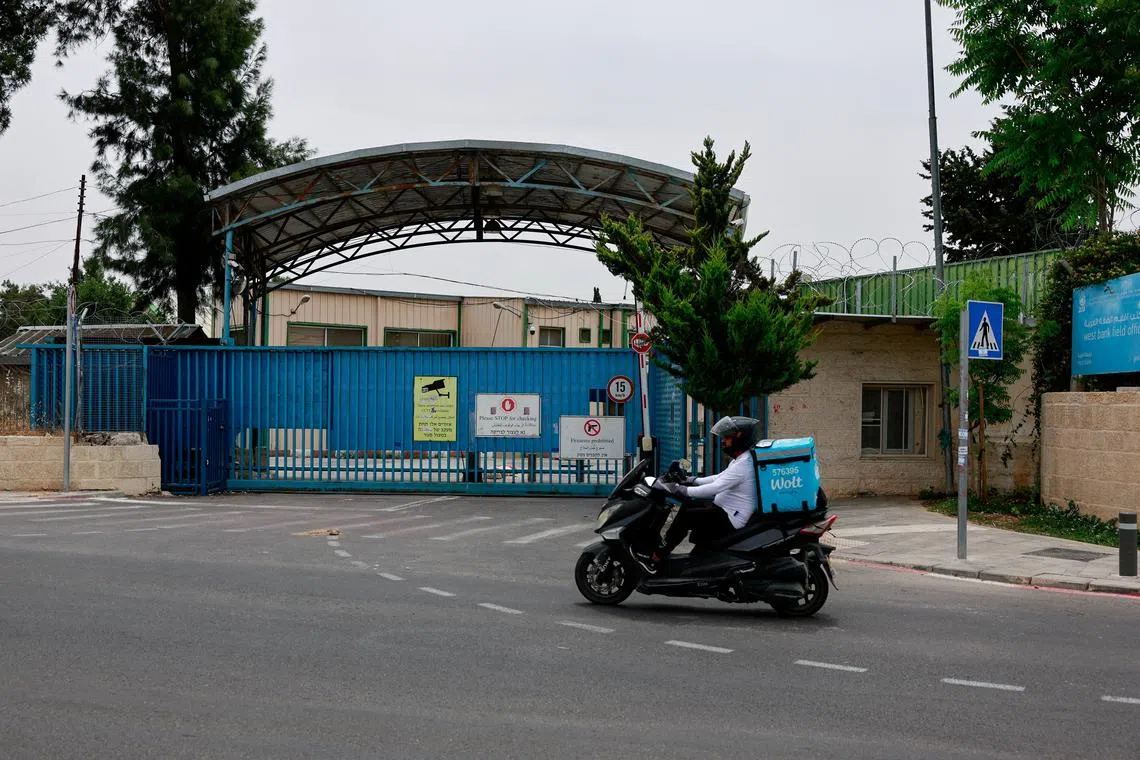 FILE PHOTO: A man drives a scooter past the UNRWA headquarters, in Jerusalem, May 10, 2024. REUTERS/Ammar Awad/File Photo