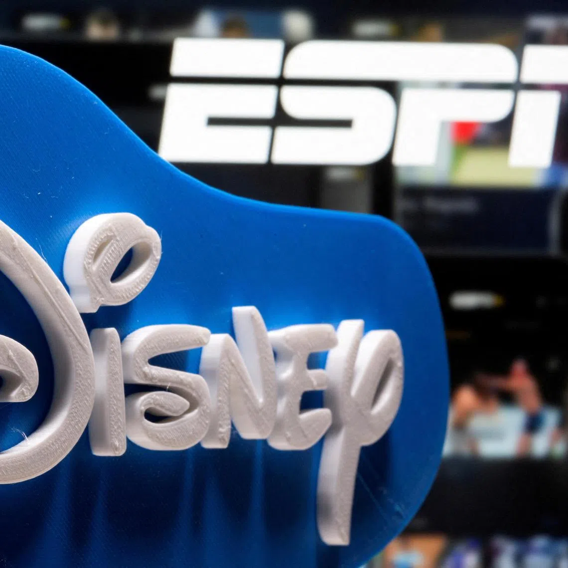 A 3D printed Disney logo is seen in front of the ESPN+ logo in this illustration.