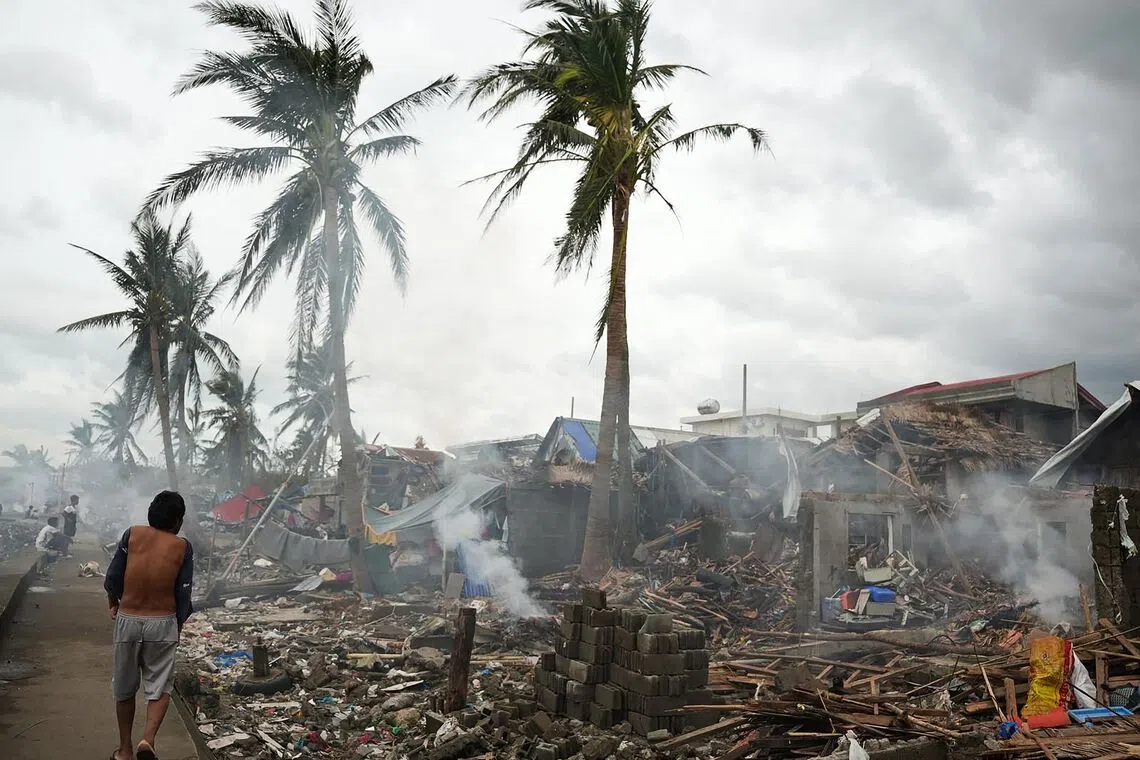 Residents burning wood from their destroyed houses near the seawall at Garchitorena in Camarines Sur province, south of Manila, Philippines on Nov 10, 2025, a day after Super Typhoon Fung-wong made landfall. 