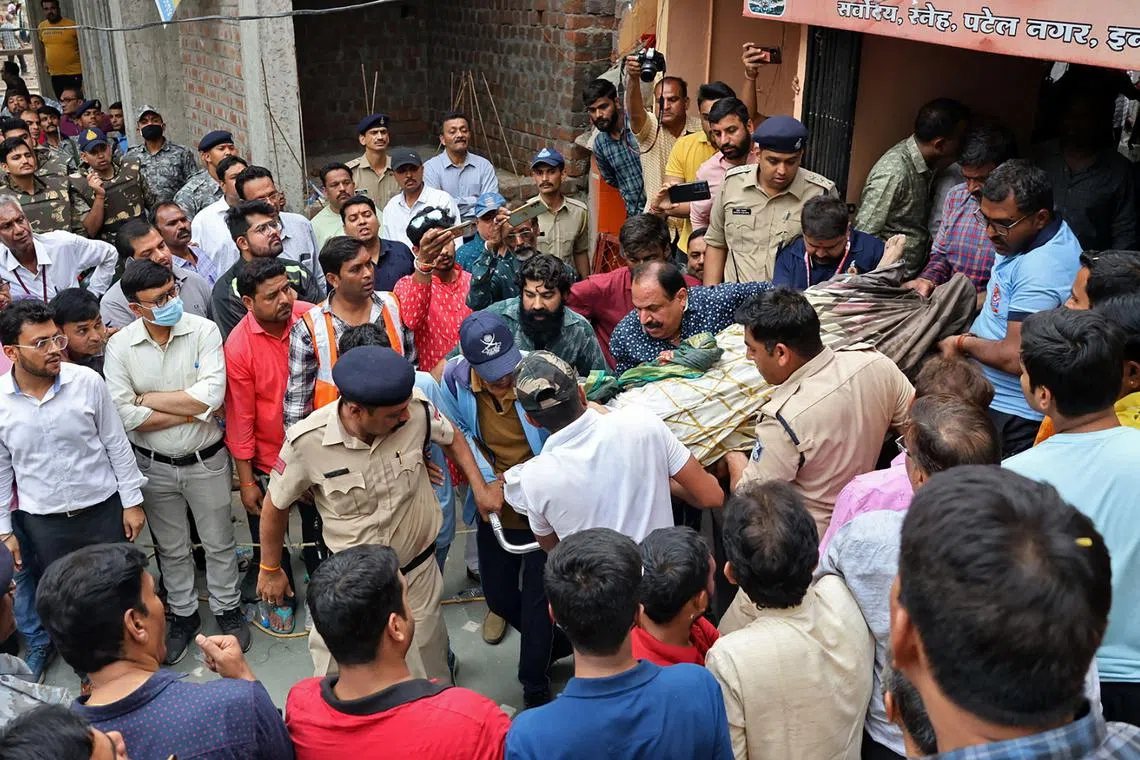 Rescue and security personnel carry a devotee on a stretcher who was injured after the floor covering a stepwell collapsed at a Hindu temple in Indore. 