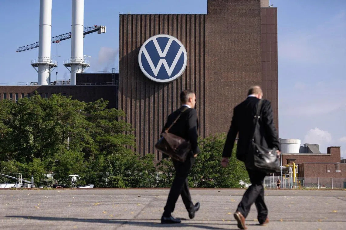 Workers pass a VW sign at the Volkswagen AG factory in Wolfsburg, Germany, on Thursday, May 23, 2024. Auto sales in Europe rose 12% in April as manufacturers including Volkswagen AG and Renault SA benefited from robust demand for plug-in and conventional cars in several major markets. Photographer: Krisztian Bocsi/Bloomberg