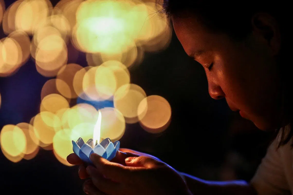 A woman holding a Krathong, a floating basket made with leaves and flowers, before placing them in a park's lagoon during the Loy Krathong festival, held as a symbolic apology and to express gratitude to the goddess of the river for the water, in Bangkok, Thailand, Nov 27, 2023. 