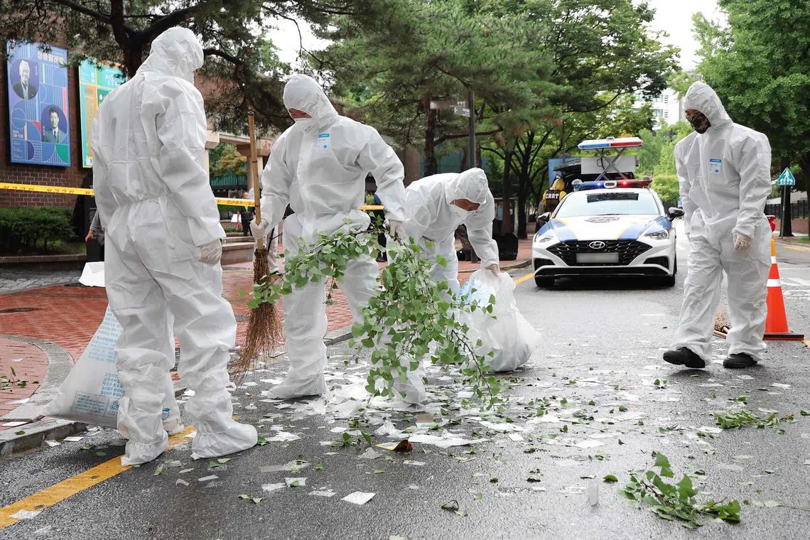 South Korean officials clean up the contents of a trash-carrying balloon sent by North Korea after it landed on a street in Seoul on July 24.