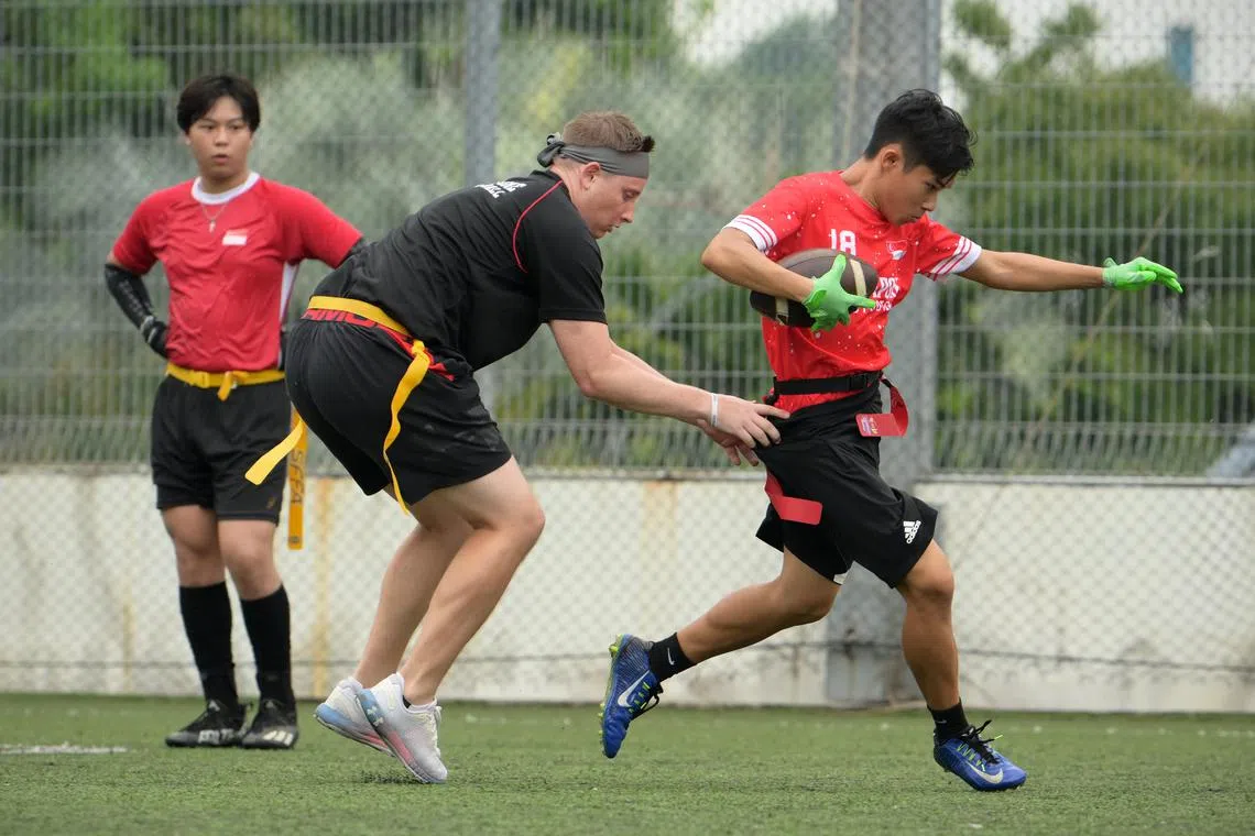 National team player Nathaniel Tan, 22, attempts to run past coach James Rosewarne (in black) during training.