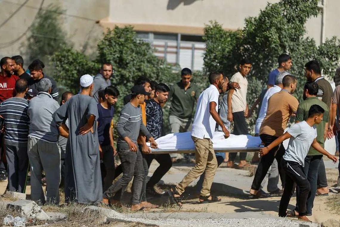 People carry the body of a Palestinian killed in Israeli strikes amid ongoing conflict between Israel and the Palestinian Islamist group Hamas, in Khan Younis in the southern Gaza Strip October 13, 2023. REUTERS/Ibraheem Abu Mustafa