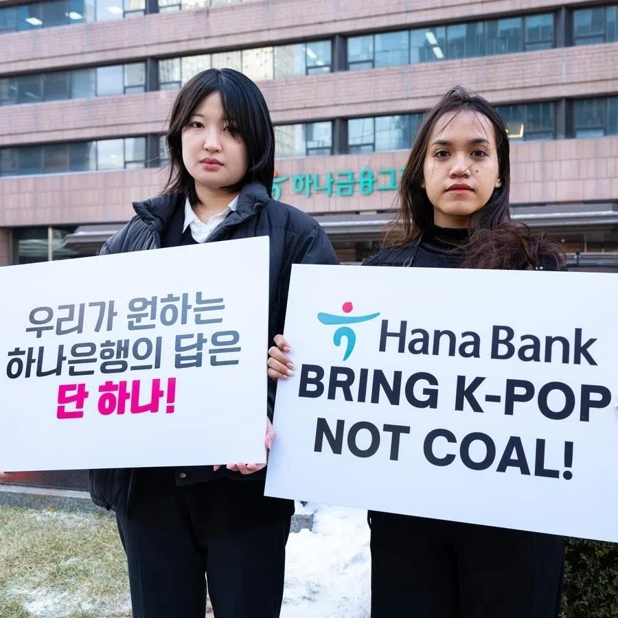 Kpop4planet's Lee Da-yeon (left) and Nurul Sarifah hold signs demanding that Hana Bank cease funding nickel projects on Feb 2.