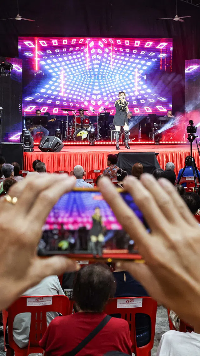 A spectator taking a video of getai singer Lin Jia Jia's performance at a hungry ghost festival getai show at Toa Payoh Industrial Park on Aug 20, 2026. ST PHOTO: BRIAN TEO