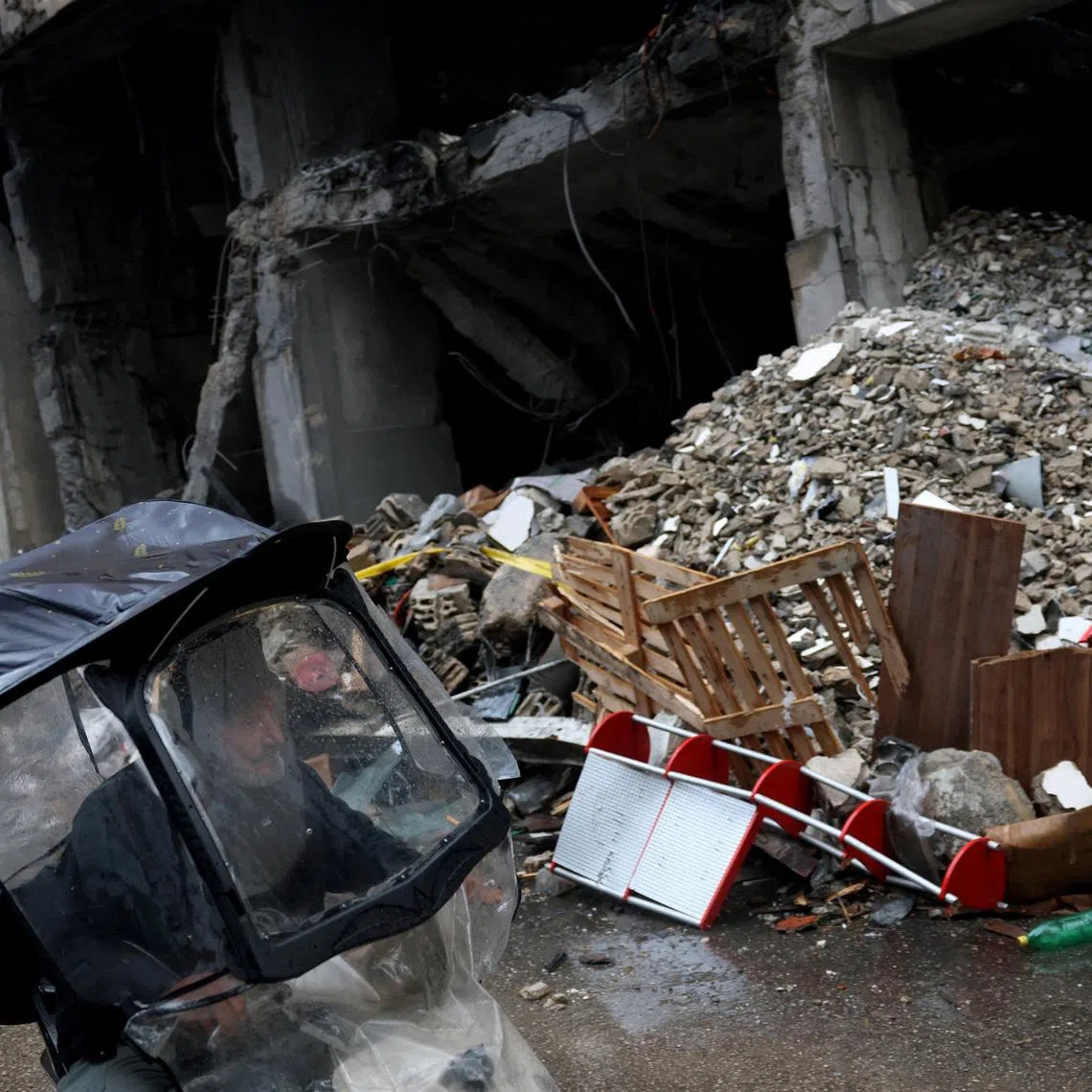 A man rides a scooter next to a damaged building in the aftermath of an Israeli strike in central Beirut, targeting what Israel said is a Hezbollah-affiliated bank, following an escalation between Hezbollah and Israel amid the U.S.-Israeli conflict with Iran, in Beirut, Lebanon, March 15, 2026. REUTERS/Claudia Greco