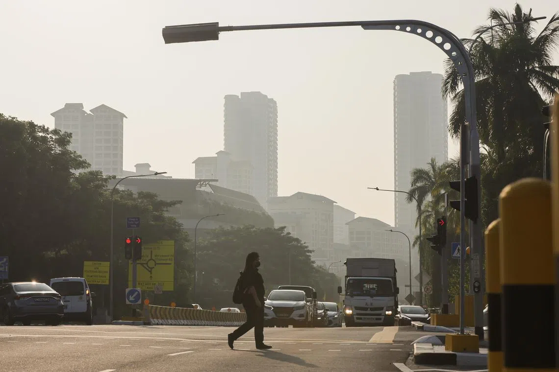 A woman crossing the road during hazy conditions along Sin Ming Ave at 7.40am on Oct 11. The 24-hour PSI as of 7.40am in the central is 85.