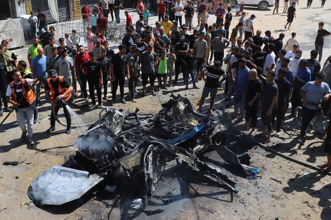 Residents gather as fire is extinguished following an Israeli airstrike that hit a vehicle in Gaza City, August 31, 2026. REUTERS/Ebrahim Hajjaj