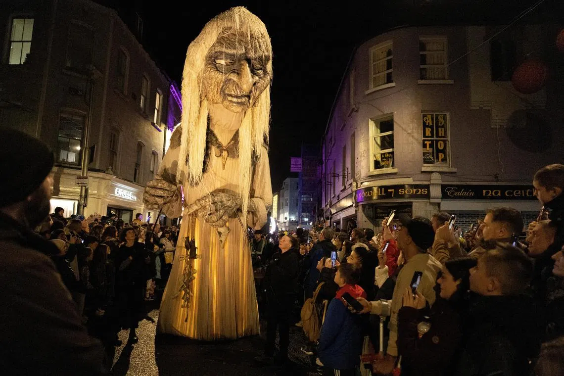 People attending as members of street performance troupe Macnas perform their Halloween parade called ‘Cnamha La Loba’, inspired by the legend of a wild wolf-woman who collects and preserves bones of animals, humans, and Gods, in Galway, Ireland on October 29, 2023. 