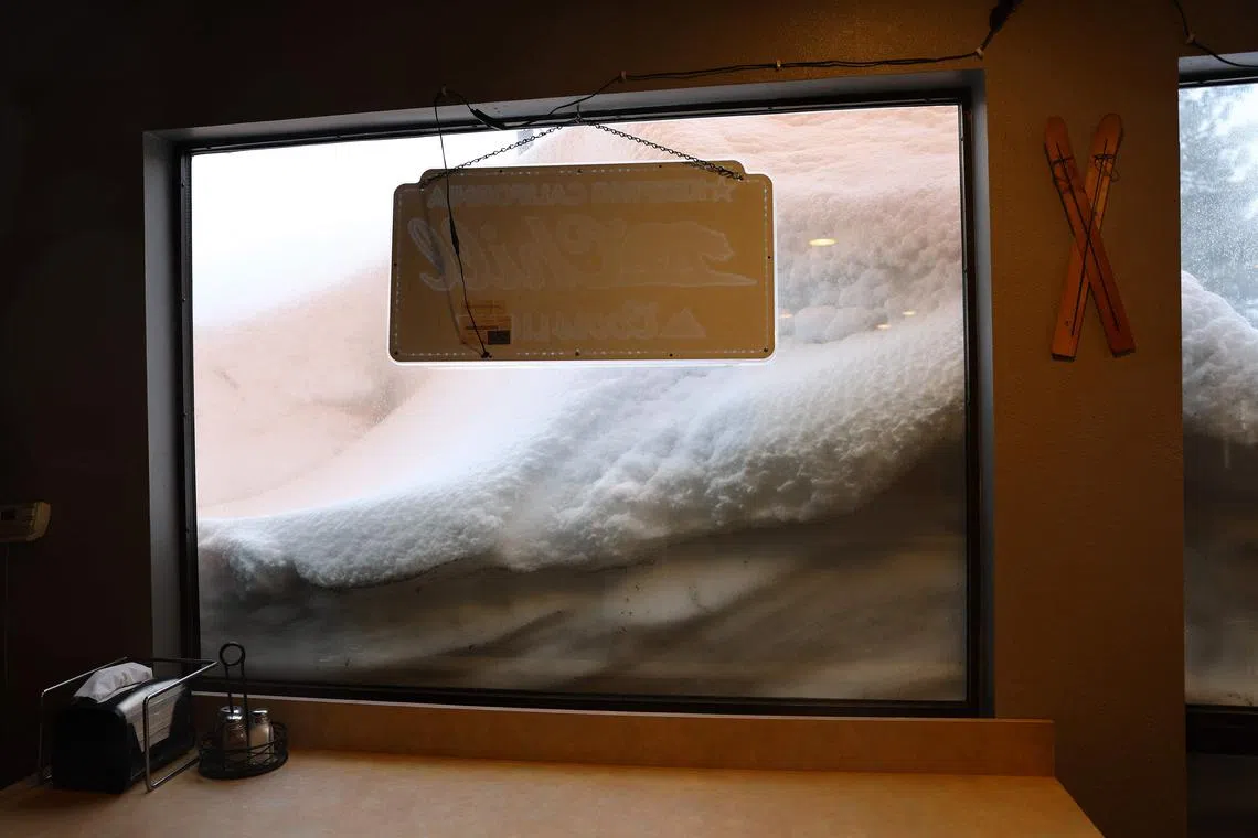 A restaurant window is blocked by a snowbank piled up from current and previous storms as snow continues to fall in the Sierra Nevada mountains, in the wake of an atmospheric river event, on March 11, 2023, in Mammoth Lakes, California. F