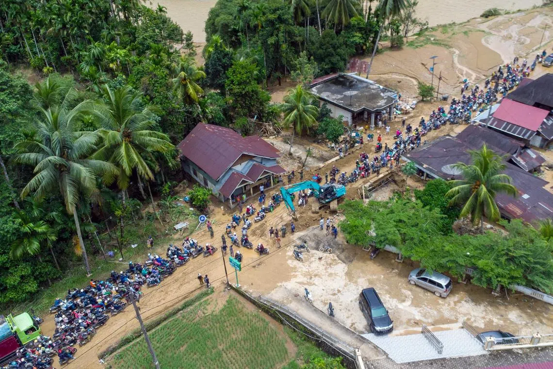 An aerial view shows motorists driving through a muddy road following flash flooding in Pesisir Selatan Regency, West Sumatra on March 9, 2024, after days of heavy rain across the province. At least 10 people were killed and 10 others were missing after flash floods and a landslide on the Indonesian island of Sumatra, a local official said on March 9. (Photo by SUTAN MALIK KAYO / AFP)