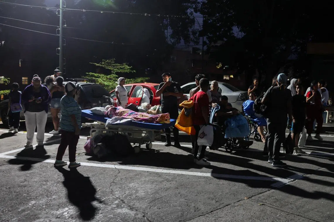 People standing next to others in wheelchairs and hospital beds on the street after an earthquake in Caracas, Venezuela, on June 24.