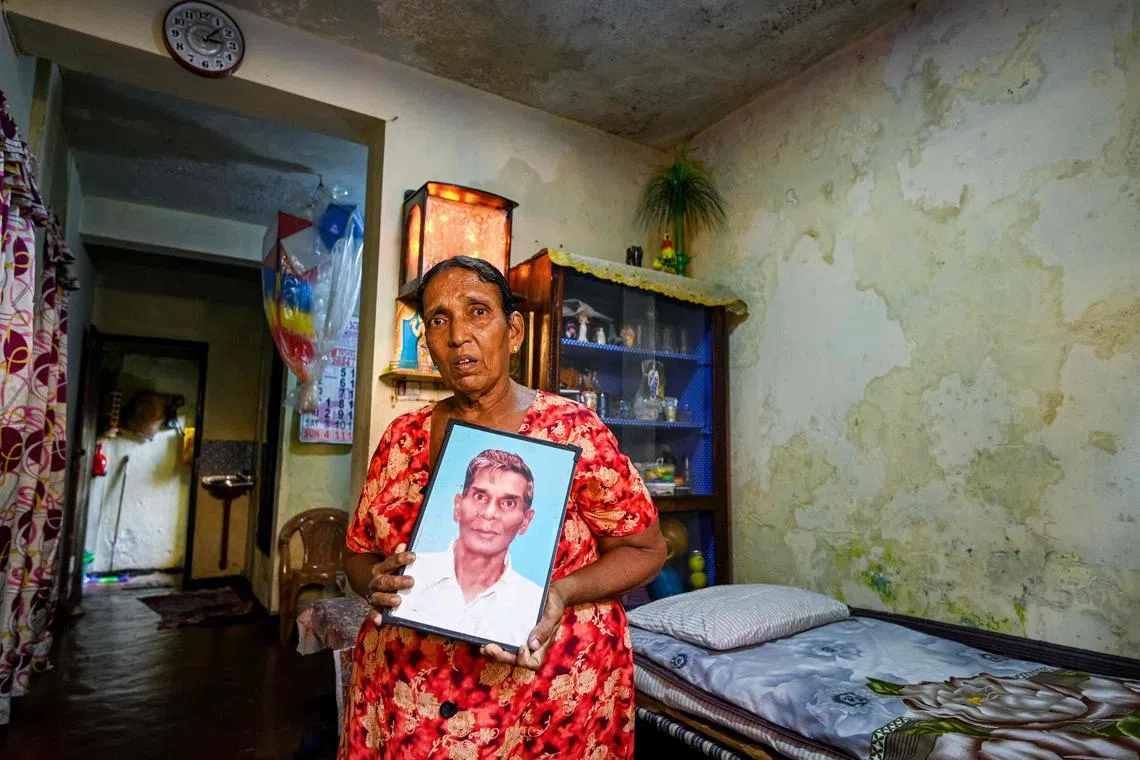 In this photograph taken on August 22, 2024, Pushpalatha, the widow of late Sri Lankan accountant Milton Perera, displays his portrait at their house in Slave Island, a suburb in Colombo. Retired accountant Milton Perera had hoped to use his vote in upcoming presidential elections to vent his fury at political mismanagement and an economic crisis that slashed healthcare. Instead, his widow Pushpalatha will cast her ballot in the September 21 polls in memory of her husband, mourning a man who died with chronic asthma unable to afford medicine. (Photo by Ishara S. KODIKARA / AFP) / To go with 'Sri Lanka-Vote-Economy-Health' FOCUS