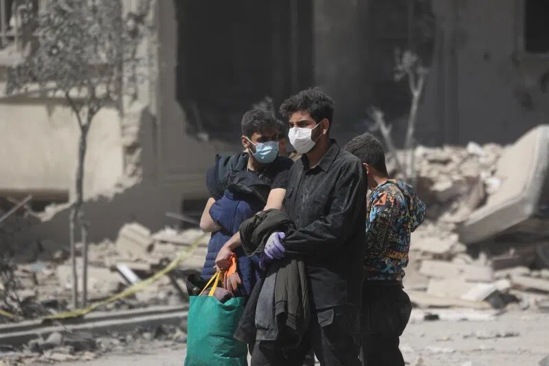 People walk in a residential neighbourhood damaged by a strike in Tehran, Iran.