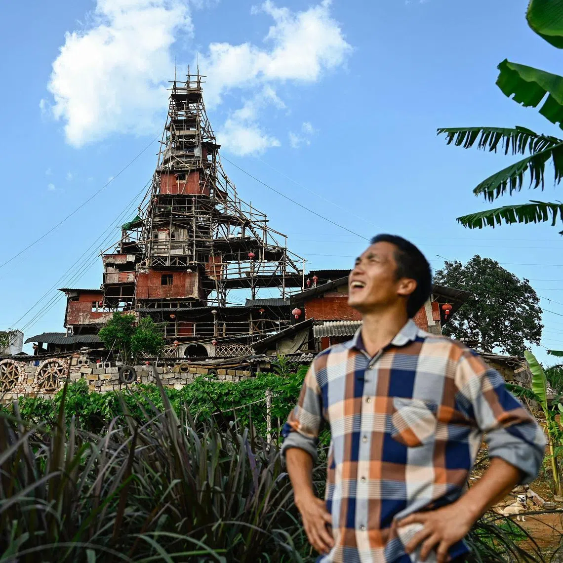 This picture taken on May 20, 2025 shows Chen Tianming standing in front of his house labelled China's strangest "nail house" -- households that refuse to move in the face of development plans -- in Xingyi, in southwest Guizhou province. Chen, 42, has spent seven years and over 100,000 yuan ($13,900) defying authorities' demolition notices to turn his family's humble stone bungalow on the outskirts of Xingyi city into a bewildering 10-storey pyramid-shaped home that has drawn comparisons on Chinese social media to the fantastical creations of Japanese animator Hayao Miyazaki. (Photo by Pedro PARDO / AFP) / TO GO WITH: China-social-politics-property, by Sam DAVIES