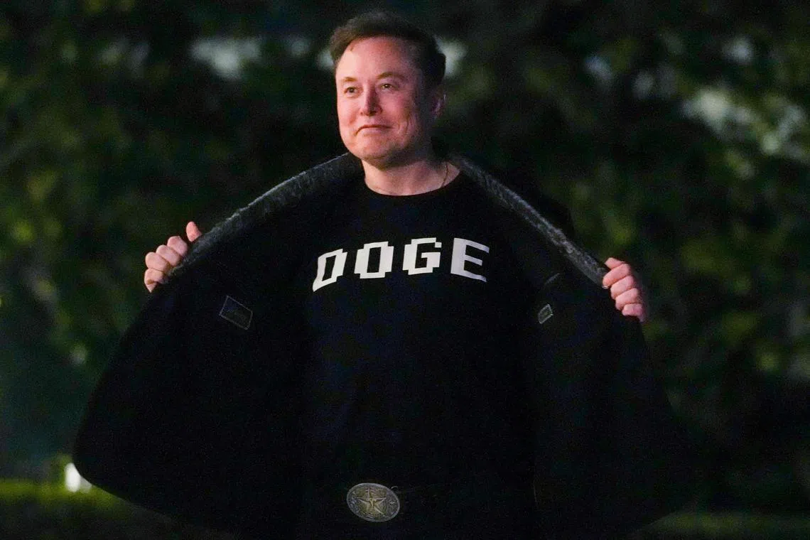 Elon Musk shows off a shirt that says "DOGE" as he walks on the South Lawn of the white House after stepping off Marine One upon arrival to the White House in Washington, DC on March 9, 2025. (Photo by Oliver Contreras / AFP)
