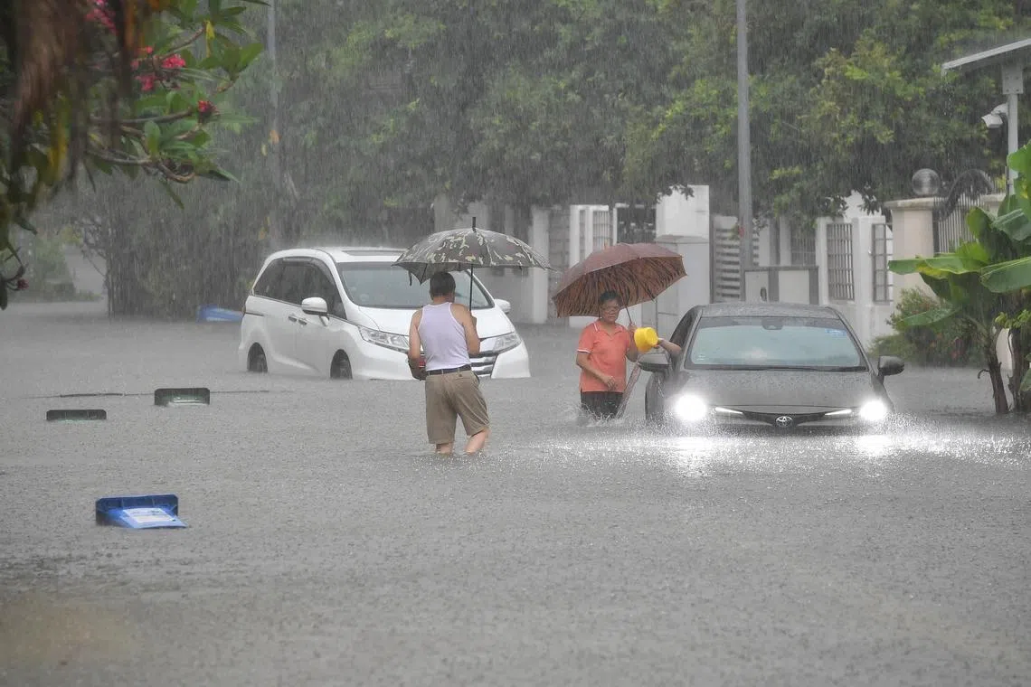 Two residents coming to a driver’s aid after his car was caught in a flash flood in Gambir Walk, off Bartley Road, on 2 Nov 2020. Flash floods occurred at three locations in Singapore from around 3pm due to intense rainfall, said national water agency PUB.